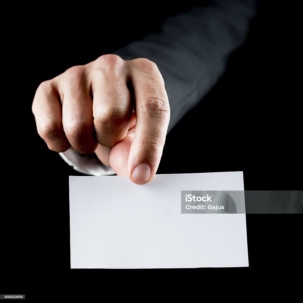 Blank business card Closeup of male hand holding a blank white business card towards you. Over black background. Adult Stock Photo
