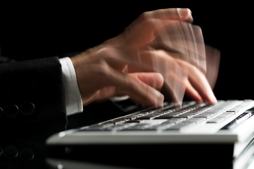 Closeup of blurred male hands typing on computer keyboard. Over black background.
