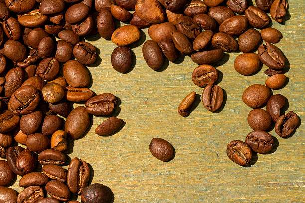 grãos de café sobre fundo de madeira - coffeetree - fotografias e filmes do acervo