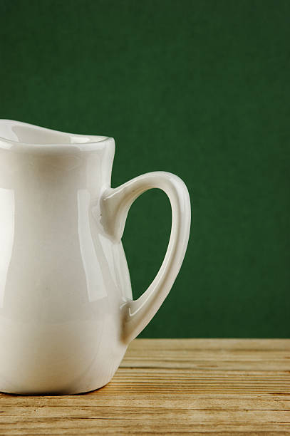 istock White jug on old wooden table over green background 505546187