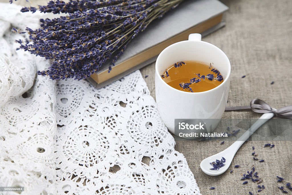 Lavender and cup of tea cup of herbal tea with a porcelain spoon and a lavender bouquet on linen fabric and a lacy cloth Blue Stock Photo