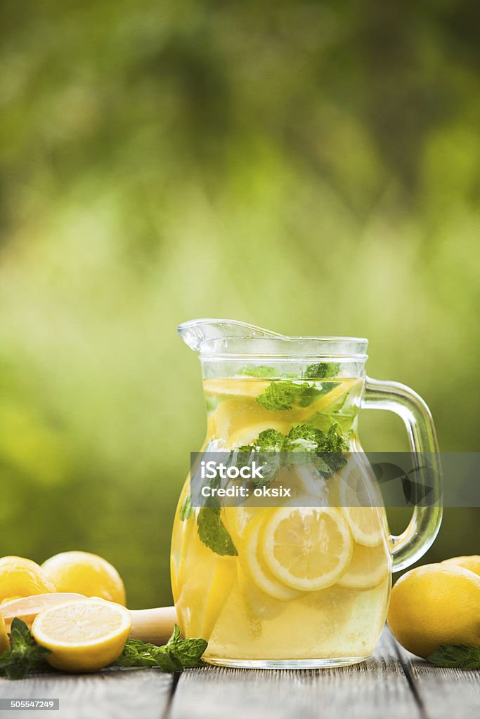 Lemonade in the jug Preparation of the lemonade drink. Lemonade in the jug and lemons with mint on the table outdoor Citrus Fruit Stock Photo