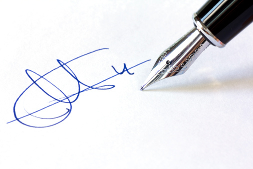 Close up shot of a fountain pen and a signature isolated on white background.