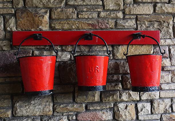 Old Red  Fire Buckets against a brick wall stock photo