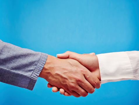 Two business hand shaking hands, as a sign for success, partnership or support, on a blue background.