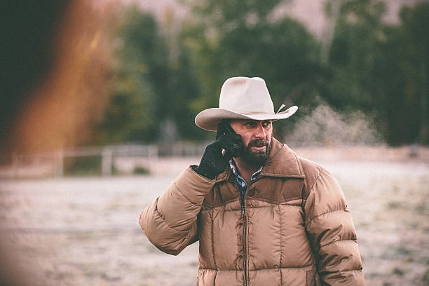 istock Cowboy talks on cell phone while working in horse pasture 505565069