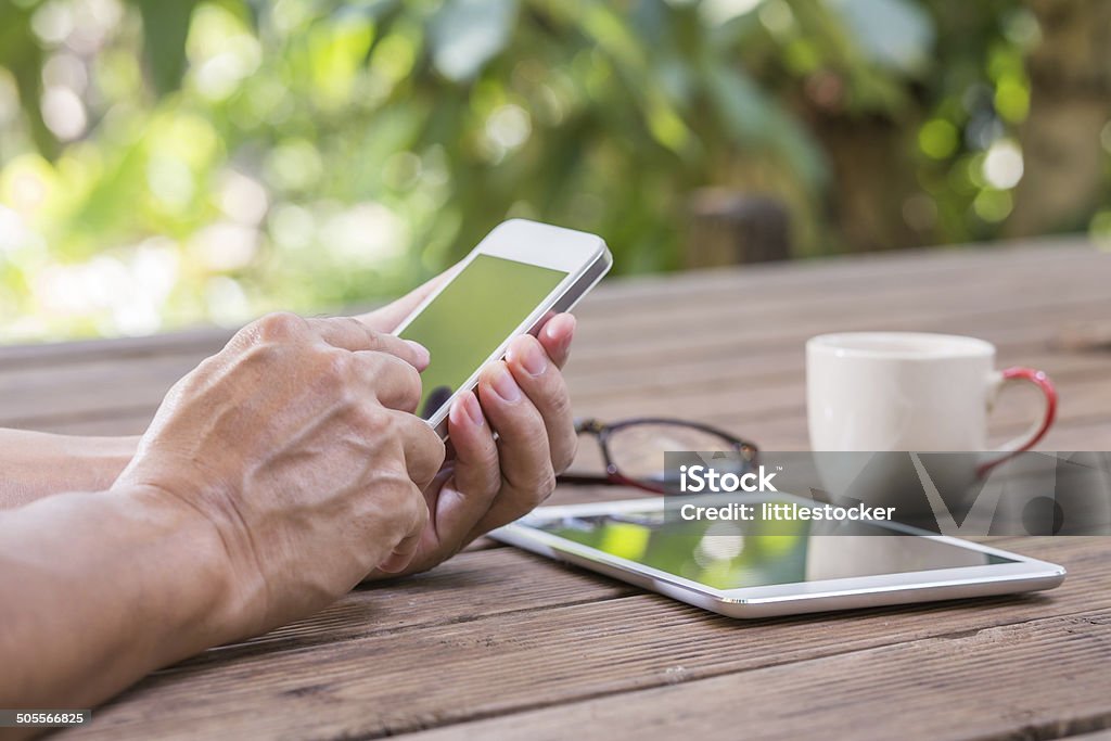 Man hands touching smart phone with green tree background Abstract Stock Photo