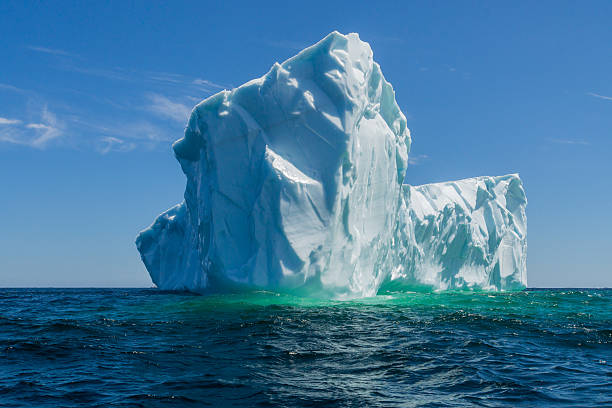 Newfoundland Tick Icebergs off the Bucket List Often a bucket list travel dream, a massive iceberg as seen off the coast of Canada, in the waters known as 'Iceberg Alley', near the island of Quirpon, Newfoundland, with a vivid blue sky and dark moody water of the North Atlantic Ocean newfoundland and labrador photos stock pictures, royalty-free photos & images