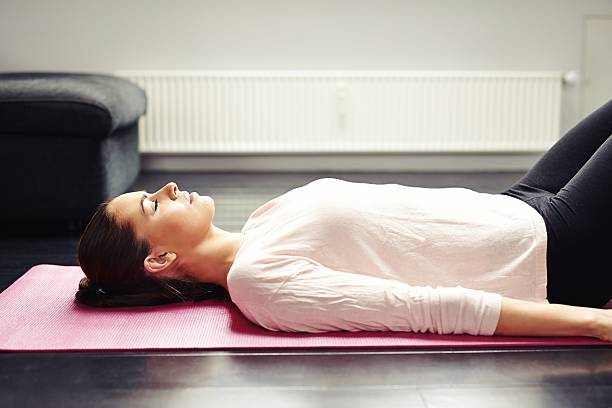 ajustement jeune femme de détente sur le tapis de yoga - supine photos et images de collection