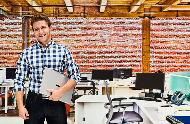 istock Smiling businessman holding laptop in office 505574376