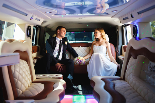 Happy bride and groom sitting in limousine