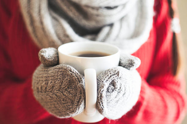 frau hände in handschuhe holding einen becher - winter weather stock-fotos und bilder