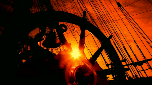 wheel of an old sailing ship at sunset