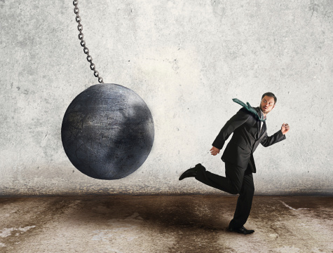 business man running away from the wrecking ball, which is the symbolic meaning