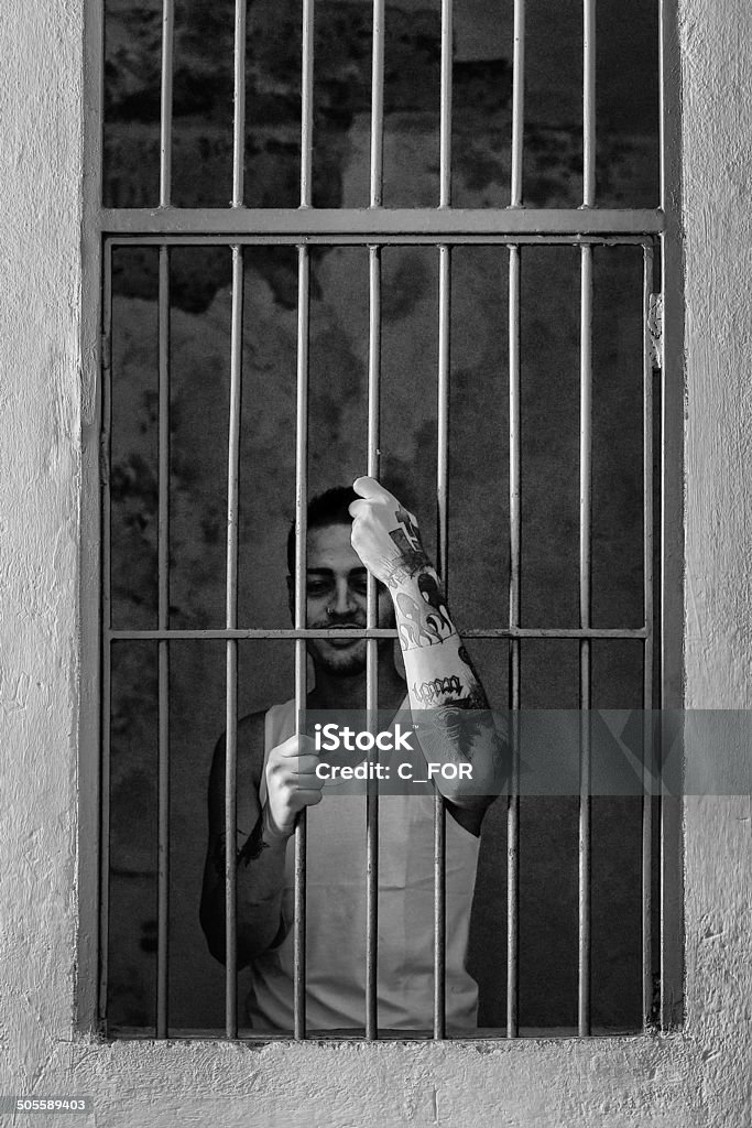 Prisoner hands - Incarceration Man behind prison bars. Prison Stock Photo