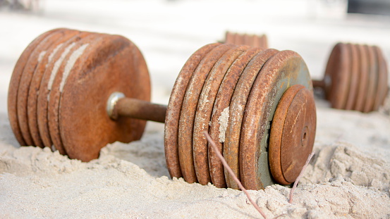 iron dumbbells in the sand outdoors