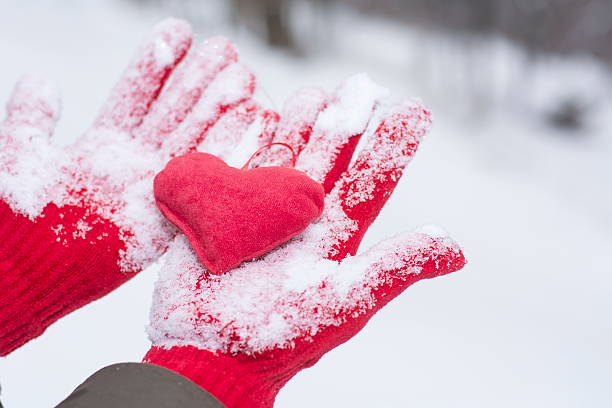 istock red gloves covered with snow holding a heart 505595952