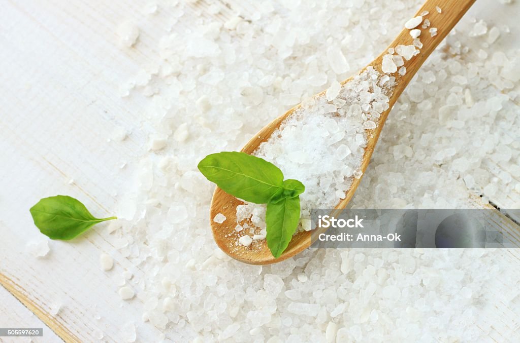 Sea salt and basil Sea salt natural close-up, white granulated fresh basil herb, wooden kitchen spoon Iodine Stock Photo