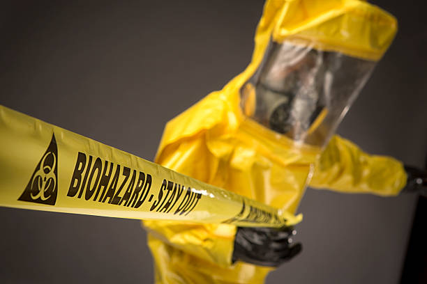 istock Man in a hazmat Suit holding biohazard warning tape 505597669