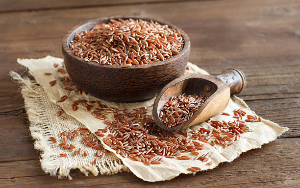 istock Uncooked Red rice in a bowl with a wooden spoon 505598470