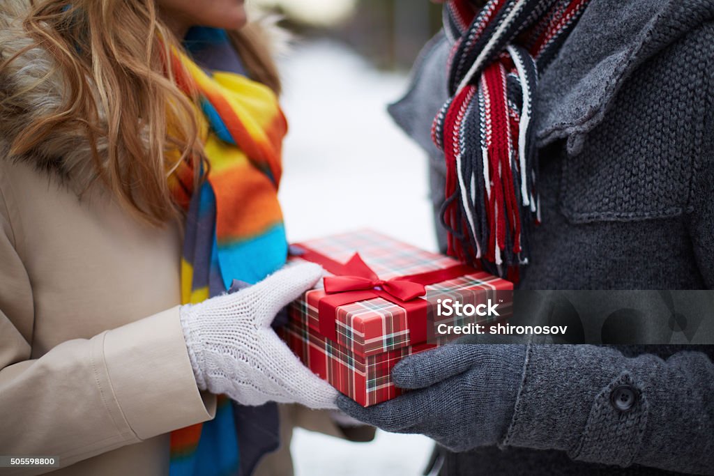 Christmas present Image of gloved hand of guy giving his girlfriend Christmas present Adult Stock Photo