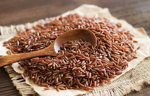 Uncooked Red rice with a wooden spoon