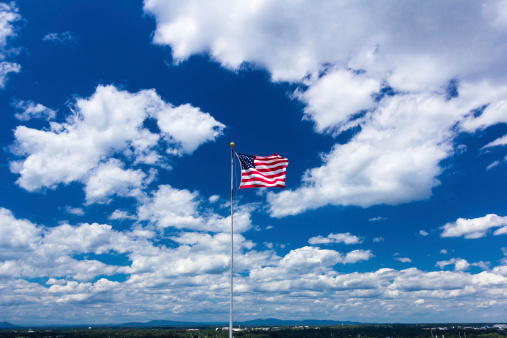 American flag against blue sky with mountains in the background.