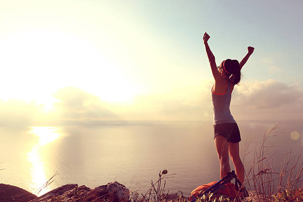 istock cheering young woman backpacker at sunrise seaside mountain peak 505604308