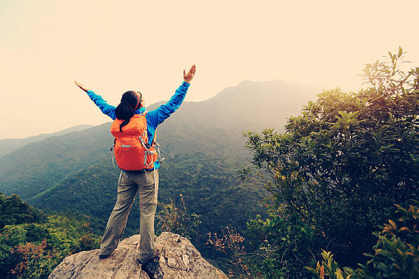 istock cheering young woman hiker open arms on mountain peak 505619780
