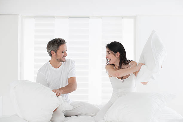 pareja de excitación almohada luchando en su casa - bed couple pillow fight men fotografías e imágenes de stock