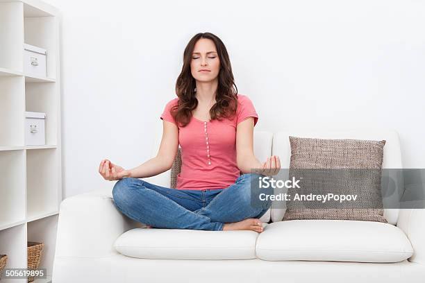 Young Woman Sitting On Couch Practicing Yoga Stock Photo - Download Image Now - Activity, Adult, Adults Only