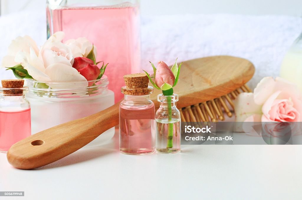 Rose water botanical hair products hair treatment, vials jars comb towel tonic home spa setting, blank space, soft delicate focus Damask Rose Stock Photo