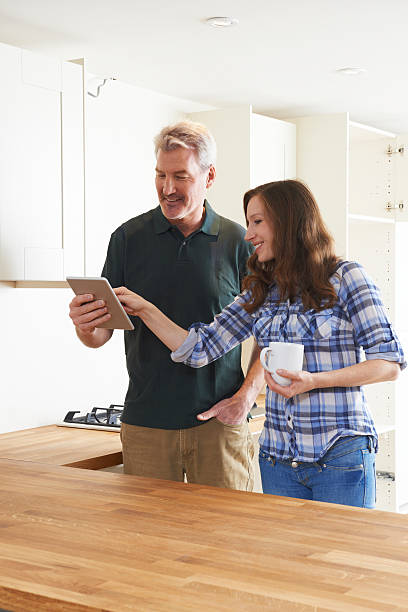 istock Woman With Carpenter Looking At Plans For Kitchen 505624690