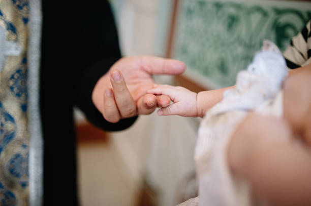 holding baby hand during christening holding baby hand during christening Orthodox baptism baptism photos stock pictures, royalty-free photos & images