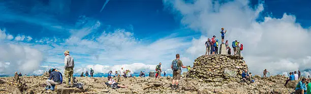 Crowds of hikers enjoying the summer sunshine on the summit of Ben Nevis, Britain's highest mountain, under panoramic blue skies, Highlands, Scotland. ProPhoto RGB profile for maximum color fidelity and gamut.