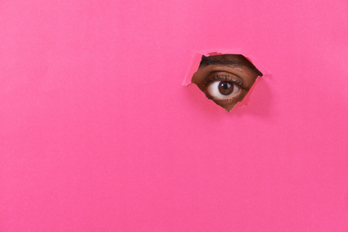 A view of a man's eye looking through a hole in some colorful paper
