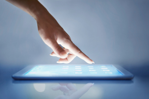 Cropped closeup of a woman's hand above a digital tablet