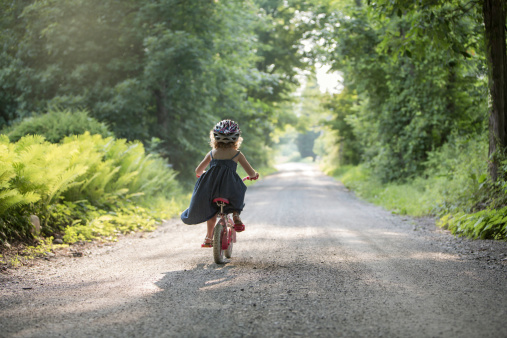 Little girl happily riding bike on rural dirt road