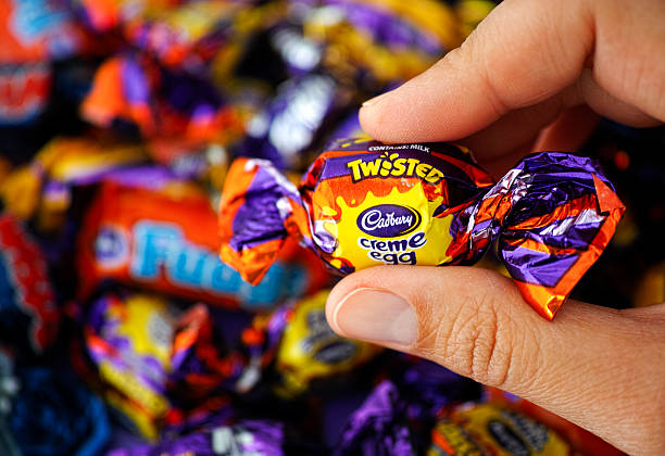 Cadbury Twisted Creme Egg candy in hand Paphos, Cyprus - November 27, 2015: Cadbury Twisted Creme Egg candy in womans hand with background of Cadbury candies. cadbury plc photos stock pictures, royalty-free photos & images