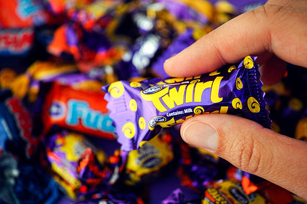 Cadbury Twirl candy in womans hand Paphos, Cyprus - November 27, 2015: Cadbury Twirl candy in womans hand with background of Cadbury candies. cadbury plc photos stock pictures, royalty-free photos & images