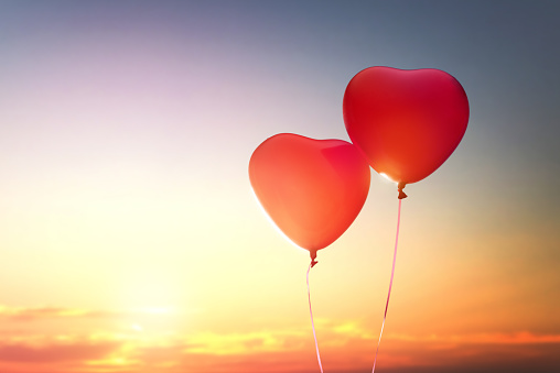 two red balloons in shape of heart on the background of sunset sky. the concept of love and Valentine's day.