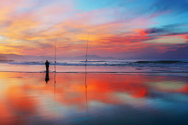 istock fisherman silhouette on beach at sunset 505641944