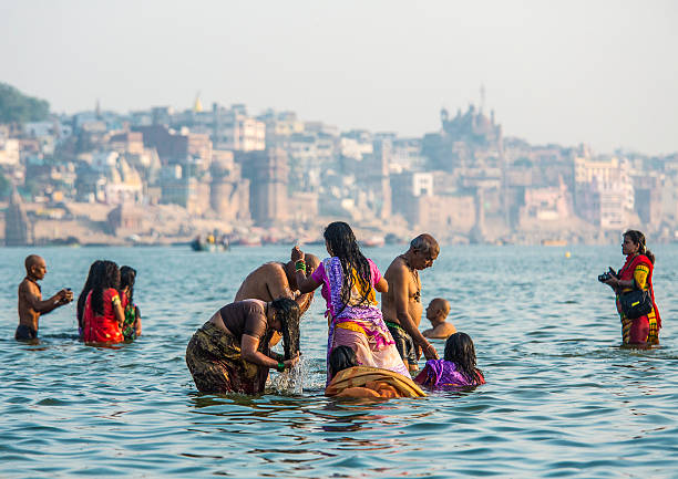 Varanasi, India - October 9, 2015: Group of people bathing in the Ganges river in Varanasi India.This is one of the oldest inhabited cities in the world and also the holiest of the seven sacred cities in Hinduism and Jainism and so the most important pilgrimage place for hindus. Many ghats, embankments made in steps, are placed in one of the river sides and it is where pilgrims perform ritual ablutions.