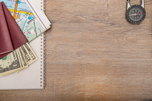 Essential travel equipments lying over wooden desk