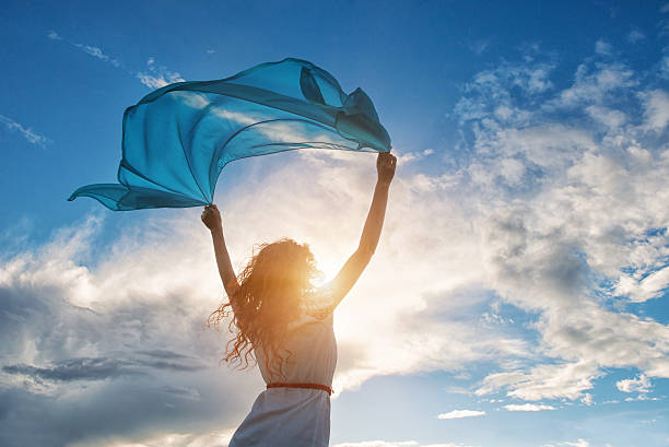 hermosa joven mujer agarrando azul bufanda en el viento - blowing fotografías e imágenes de stock