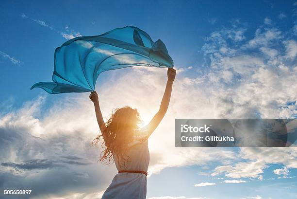 Hermosa Joven Mujer Agarrando Azul Bufanda En El Viento Foto de stock y más banco de imágenes de Mujeres