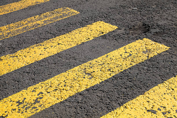 istock Pedestrian crossing road marking, yellow lines on gray asphalt 505651077