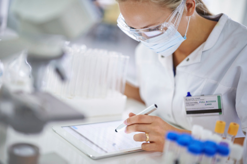 A young researcher recording her findings on a tablet in the lab