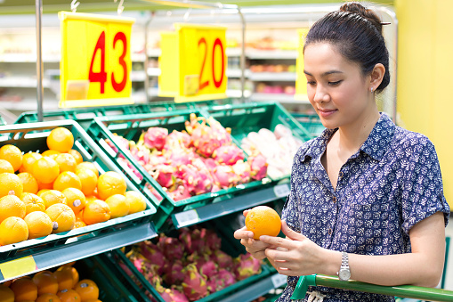Asian woman choosing oranges in the supermarket