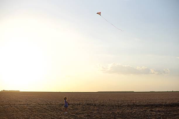 istock Little Girl Flying a Kite Against a Sunset 505662920